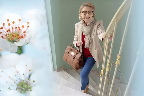Frau die eine Treppe hinaufgeht, umringt von einem Composing aus Weißdornblüten