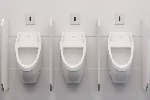  Drei Urinale an der Wand einer öffentlichen Herren-Toilette
