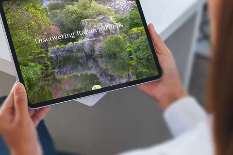 Aufsicht auf ein Tablet mit der Website der Garden Route Italia, dass eine junge Frau in den Händen hält