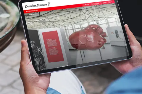 Aufsicht auf ein Tablet mit der Website des Deutschen Museums, dass eine Junge Frau in den Händen hält
