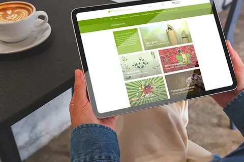 Aufsicht auf ein Tablet mit der Website "Plantainment", dass eine Junge Frau in den Händen hält