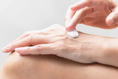 Detailaufnahme der Hände einer Frau beim Eincremen um die Wundheilung zu beschleunigen