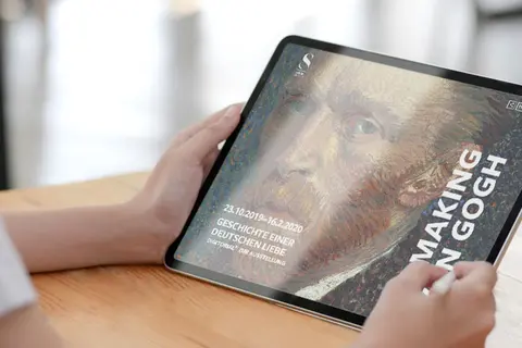 Aufsicht auf ein Tablet mit der Website des Städelmuseums, dass eine junge Frau in den Händen hält