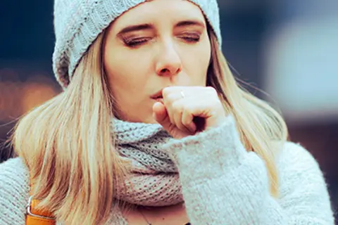 Junge Frau, die sich wegen einer Bronchitis in die Faust hustet