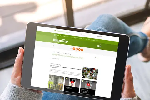 Aufsicht auf ein Tablet mit geöffneter Website des Blattgeflüster Fotowettbewerbs 2023, dass eine junge Frau in den Händen hält