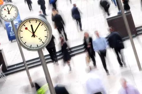 Menschenmenge in einer Fußgängerzone mit mehreren Standuhren