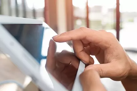 Nahaufnahme einer Hand, die auf ein Tablet tippt