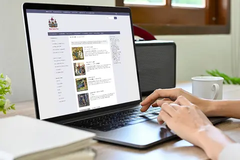 Aufsicht auf ein Laptop mit geöffneter Website des Märchenatlas, auf dem eine Frau auf der Tastatur tippt