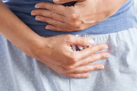 Frau mit Beschwerden hält sich den Bauch