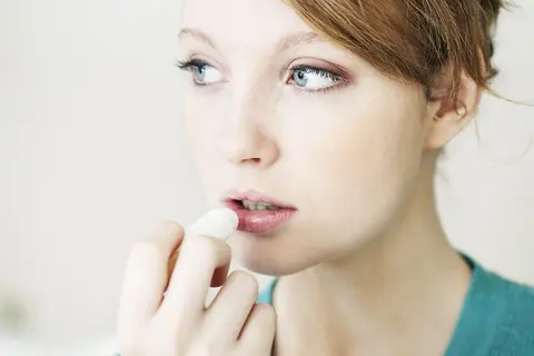 Eine junge Frau pflegt ihre Lippen mit einem Pflegestift