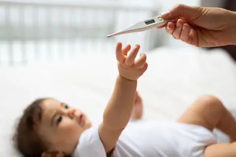 Baby greift nach dem Fieberthermometer