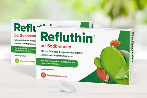 Refluthin®-Packungen auf einem Tisch mit davor liegenden Kautabletten