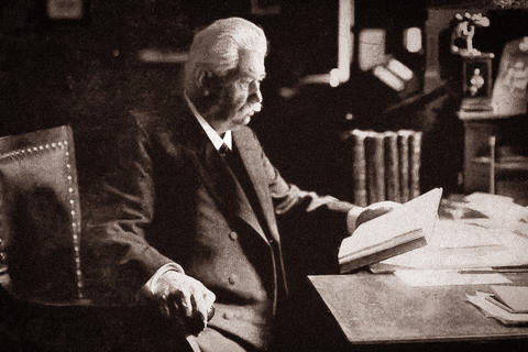 Herr Dr Willmar Schwabe sitzt an Schreibtisch mit Buch und liest