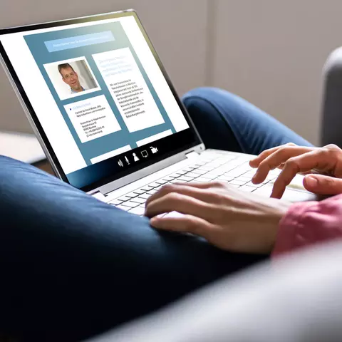 Aufsicht auf ein Laptop mit geöffneter Website der Interessensgemeinschaft „Integrative Liste Bayern“, die sich eine junge Frau anschaut