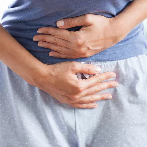 Frau mit Beschwerden hält sich den Bauch