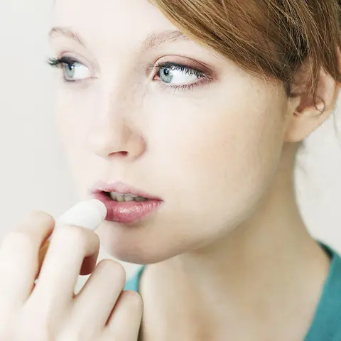 Eine junge Frau pflegt ihre Lippen mit einem Pflegestift