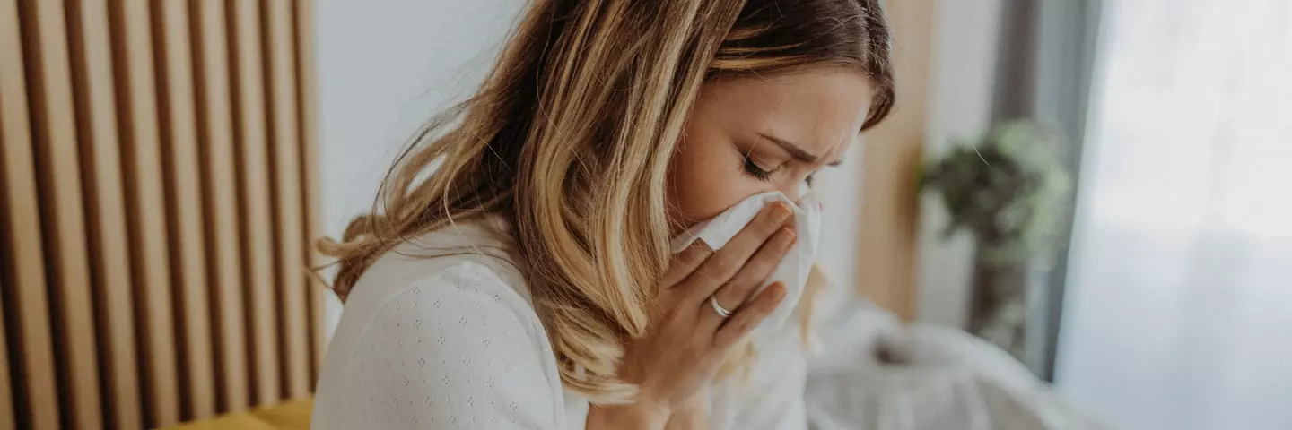 Eine Frau, die sich mit einem Taschentuch die Nase putzt.