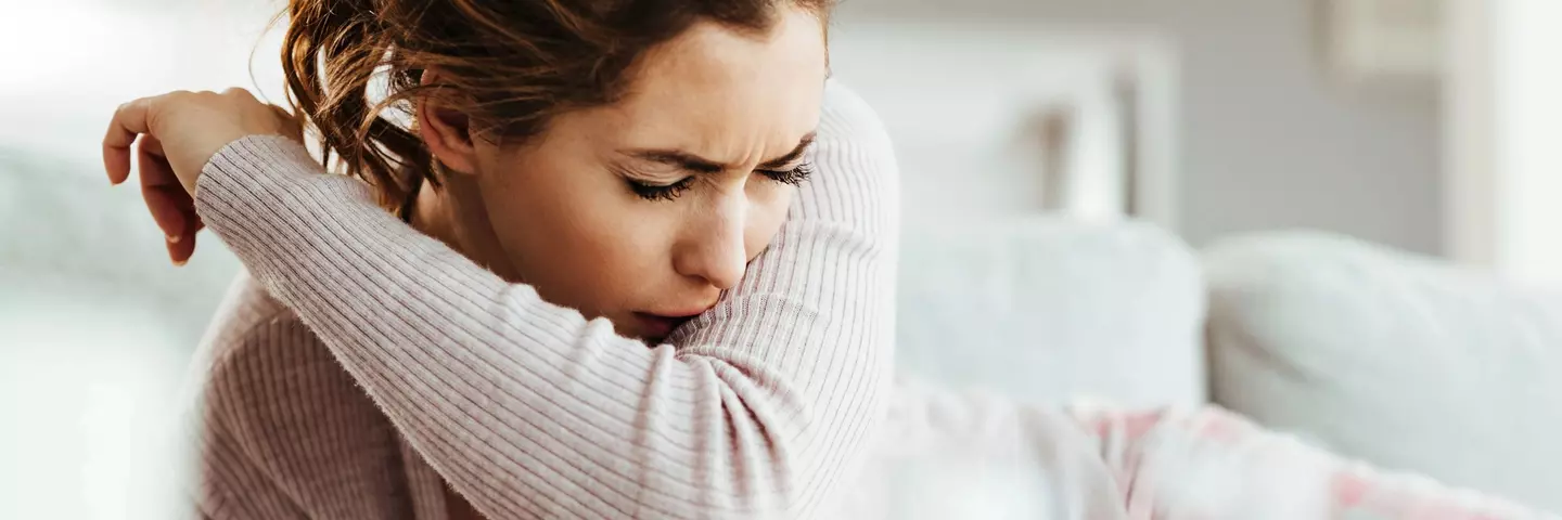 Frau hustet in die Armbeuge