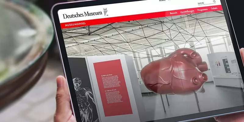 Aufsicht auf ein Tablet mit der Website des Deutschen Museums, dass eine Junge Frau in den Händen hält
