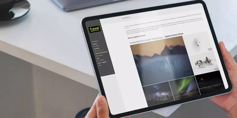 Aufsicht auf ein Tablet mit geöffneter Website "Travel Photographer of The Year", dass eine junge Frau in den Händen hält