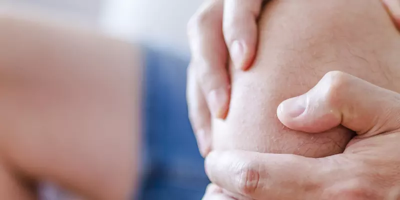 Ein Mann hält sich das Knie wegen Arthrose-Schmerzen