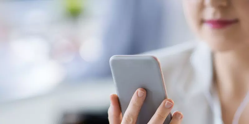 Eine junge Frau hört mit einem Kopfhörer einen Podcast auf Ihrem Smartphone