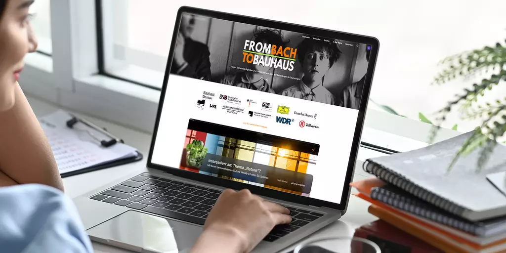 Aufsicht auf ein Laptop mit geöffneter Website artsandculture.google.com, die sich eine junge Frau anschaut