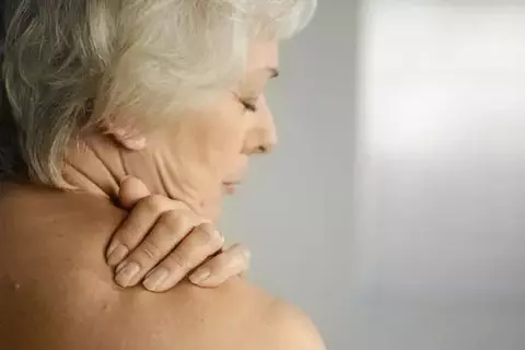 Ältere Dame reibt sich die schmerzende Schulter ein