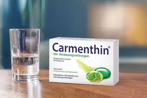 Carmenthin Packung und ein Wasserglas auf einem Tisch stehend