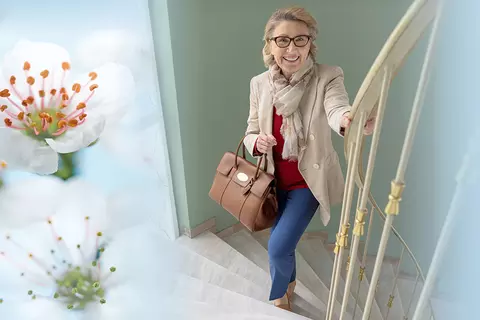 Frau die eine Treppe hinaufgeht, umringt von einem Composing aus Weißdornblüten