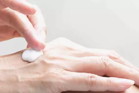 Detailaufnahme einer Frau, die sich die Hände eincremt