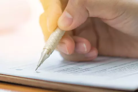 Hand mit einem Stift die einen Testbogen ausfüllt