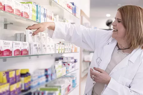 Eine Apothekerin stellt Produktpackungen von Dr. Willmar Schwabe in die Sichtwahl