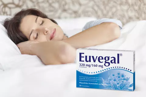 Eine Frau liegt im Bett und lächelt zufrieden im Schlaf