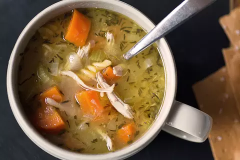 Hühnersuppe mit Karotten und Zwiebeln in einer Tasse