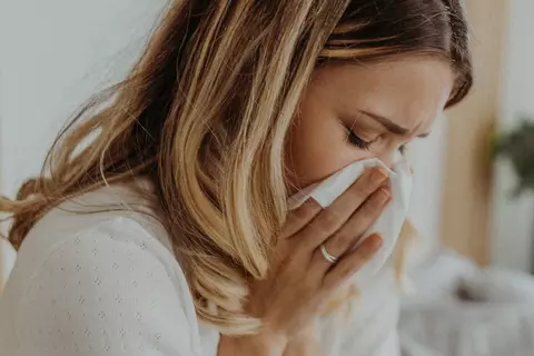Eine Frau, die sich mit einem Taschentuch die Nase putzt.
