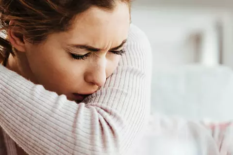 Frau hustet in die Armbeuge