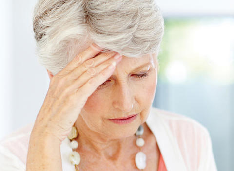 Ältere Dame hält sich wegen Schwindel die Hand an die Stirn