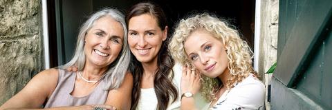 Drei Frauen blicken lächelnd in die Kamera
