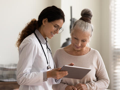 Eine Ärztin erklärt einer Patientin Gleichgewichtsübungen am Tablet