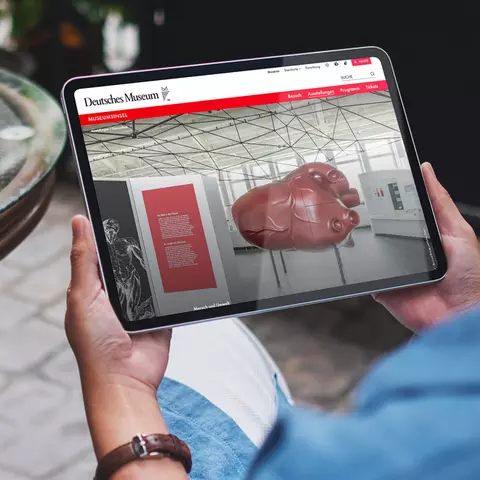 Aufsicht auf ein Tablet mit der Website des Deutschen Museums, dass eine Junge Frau in den Händen hält