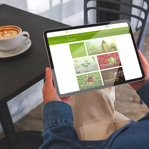 Aufsicht auf ein Tablet mit der Website "Plantainment", dass eine Junge Frau in den Händen hält