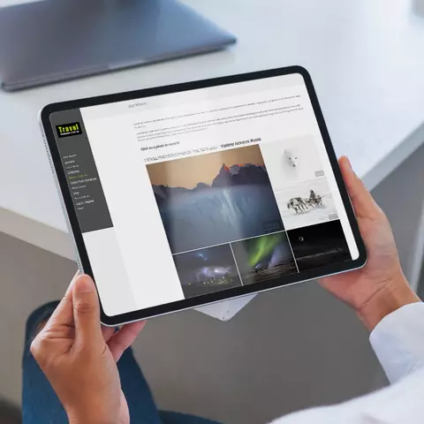 Aufsicht auf ein Tablet mit geöffneter Website "Travel Photographer of The Year", dass eine junge Frau in den Händen hält