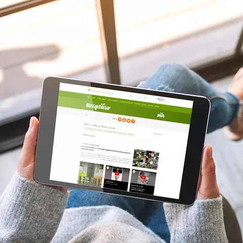 Aufsicht auf ein Tablet mit geöffneter Website des Blattgeflüster Fotowettbewerbs 2023, dass eine junge Frau in den Händen hält