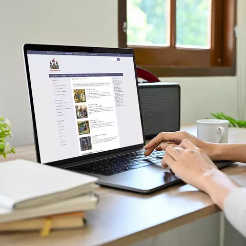 Aufsicht auf ein Laptop mit geöffneter Website des Märchenatlas, auf dem eine Frau auf der Tastatur tippt