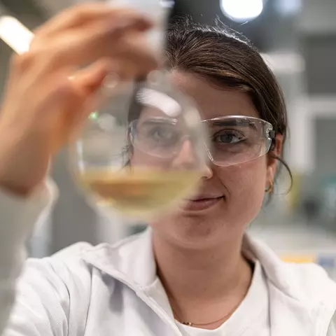 Eine Laborantin prüft eine Substanz in einem Stehkolben