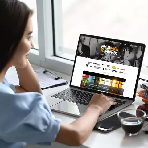 Aufsicht auf ein Laptop mit geöffneter Website artsandculture.google.com, die sich eine junge Frau anschaut