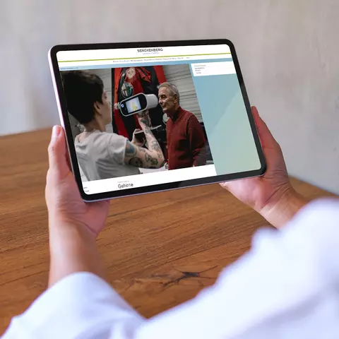 Aufsicht auf ein Tablet mit geöffneter Website des Senckenberg Naturmuseums, dass eine junge Frau in den Händen hält